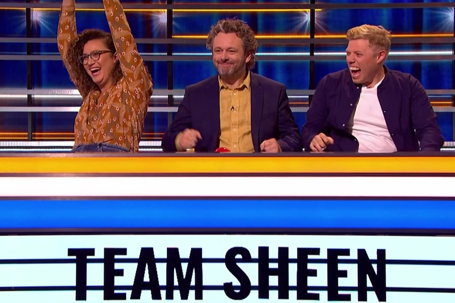 Rose Matafeo, Michael Sheen and Rob Beckett are celebrating a win, sitting in a row at a desk with a sign that reads Team Sheen 